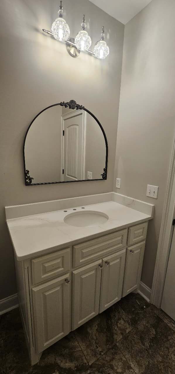 A bathroom with a sink, mirror, and light fixture.