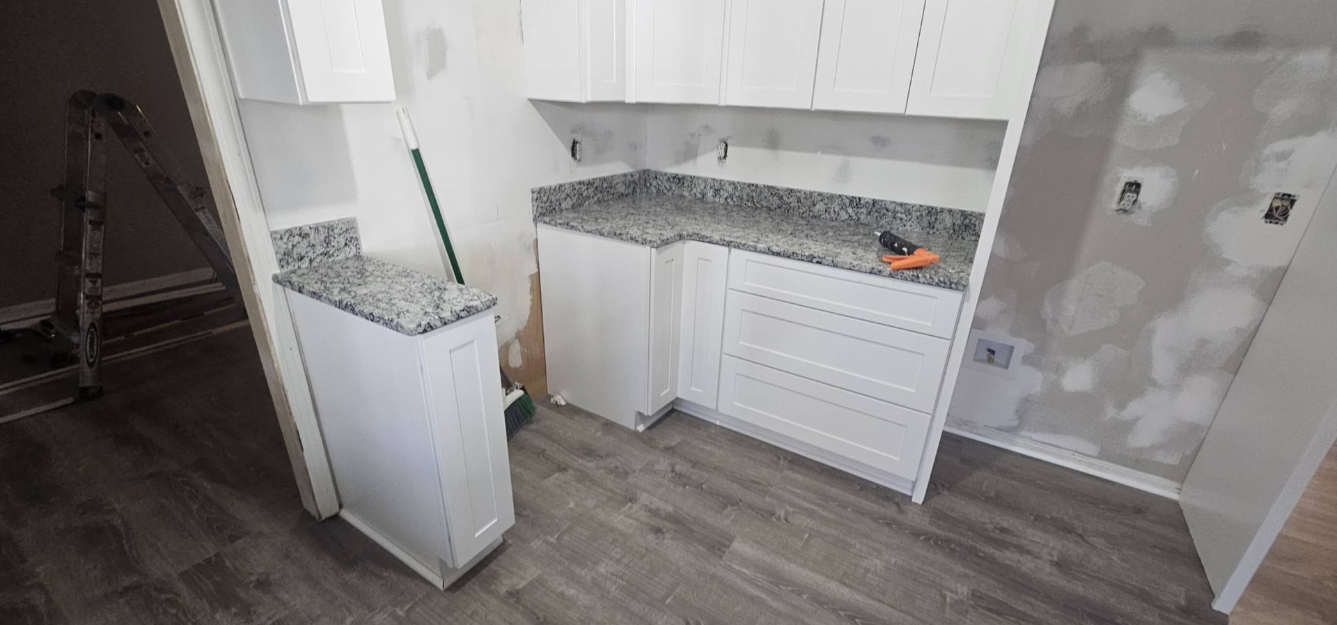 A kitchen with white cabinets and granite counter tops is being remodeled.