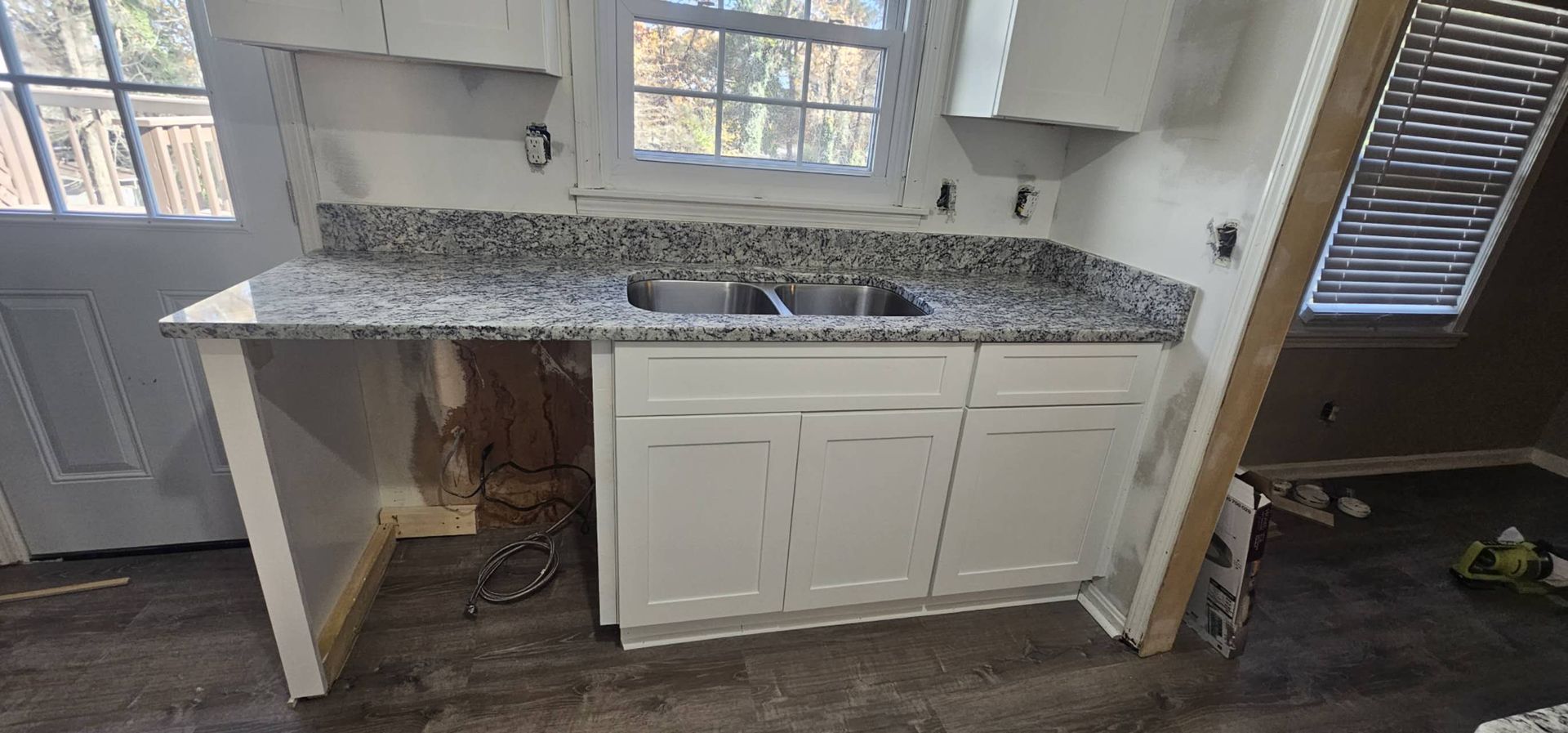 A kitchen with a sink, cabinets, and granite counter tops.
