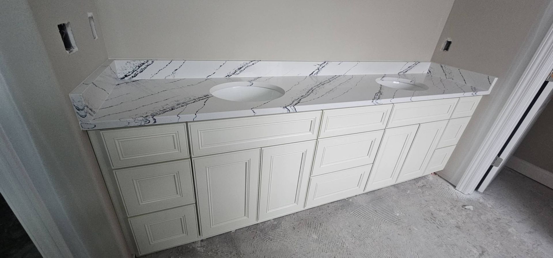 A bathroom vanity with two sinks and cabinets in a room.