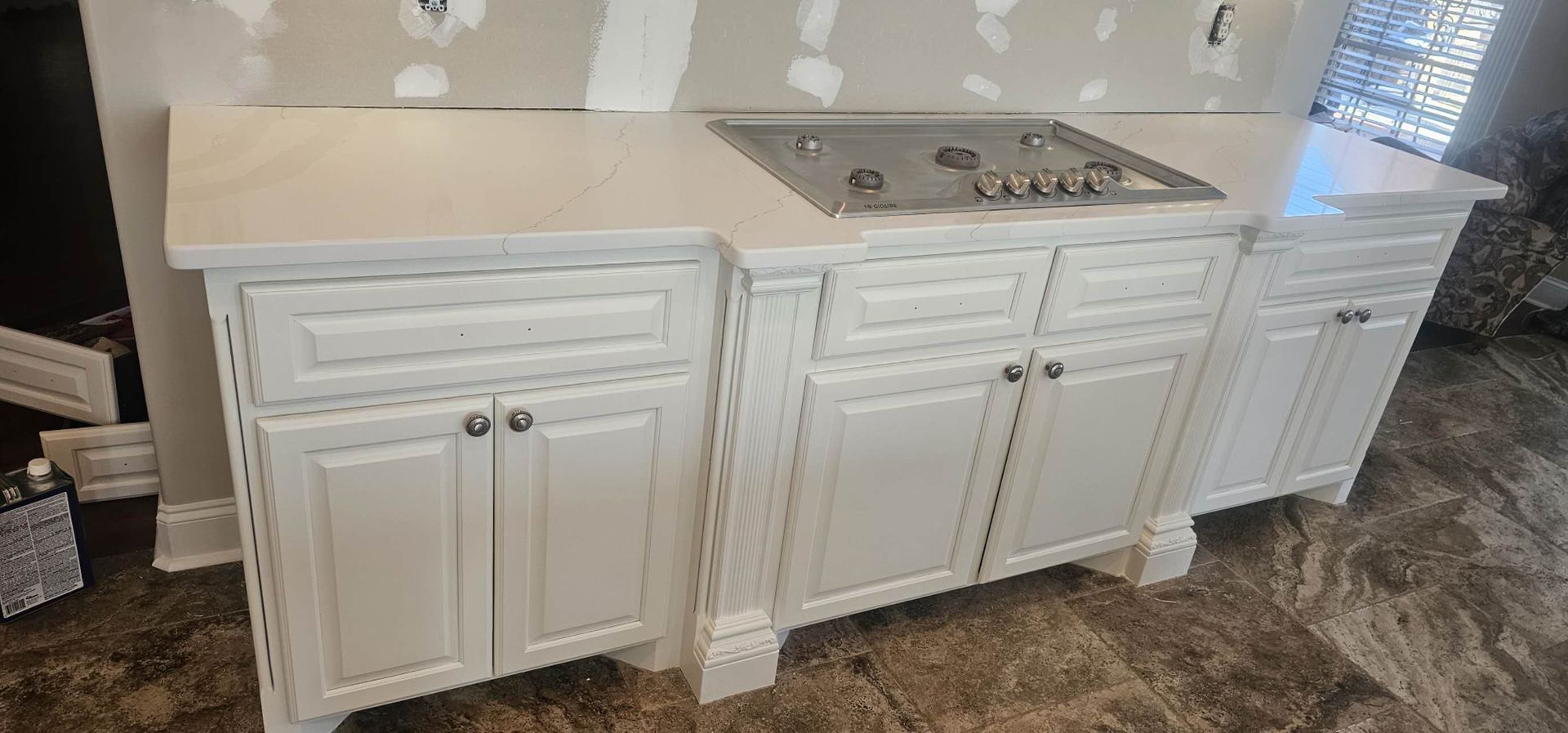 A kitchen with white cabinets and a stove top oven.