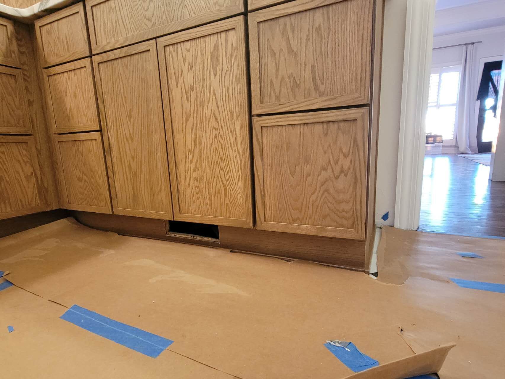 A kitchen with wooden cabinets and blue tape on the floor.
