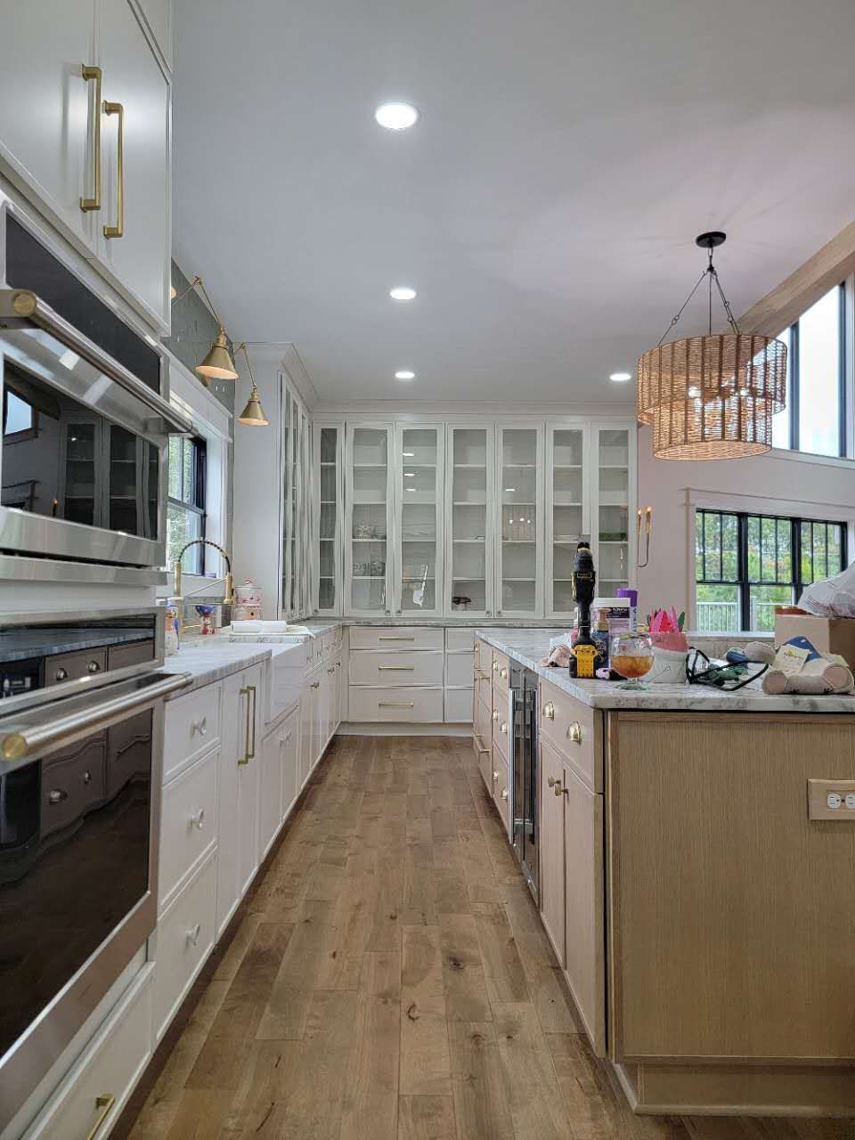 A kitchen with white cabinets, wooden floors, stainless steel appliances, and a large island.
