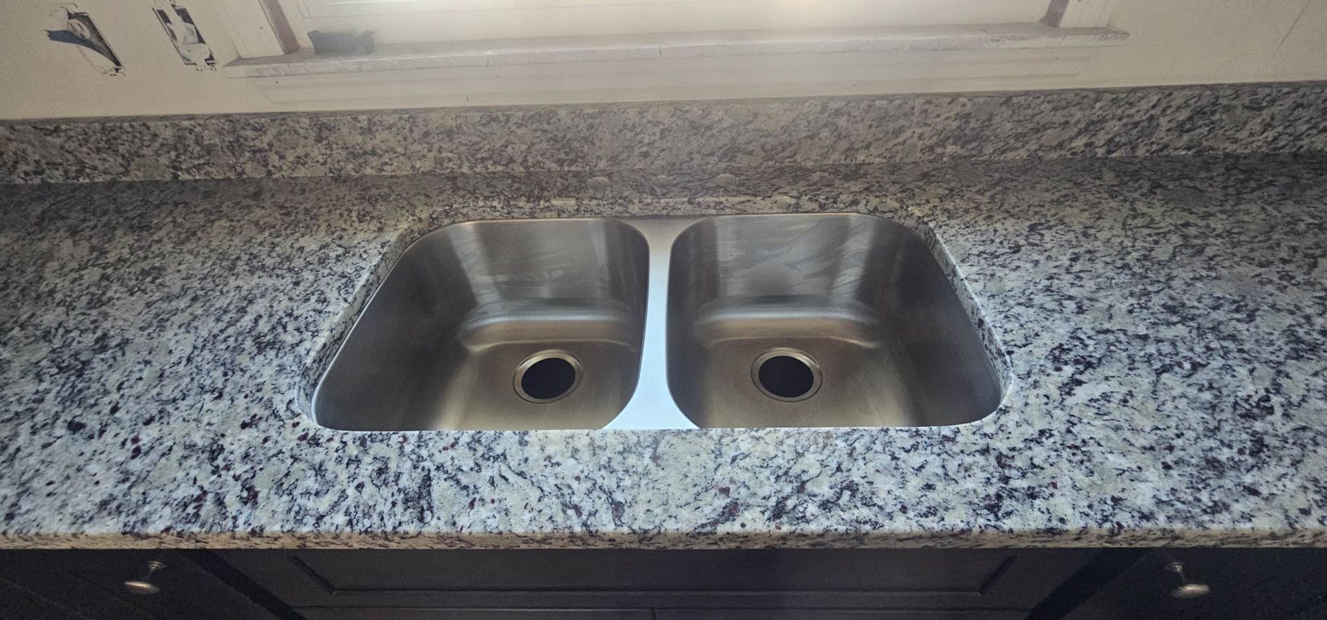 A kitchen sink is sitting on top of a granite counter top.