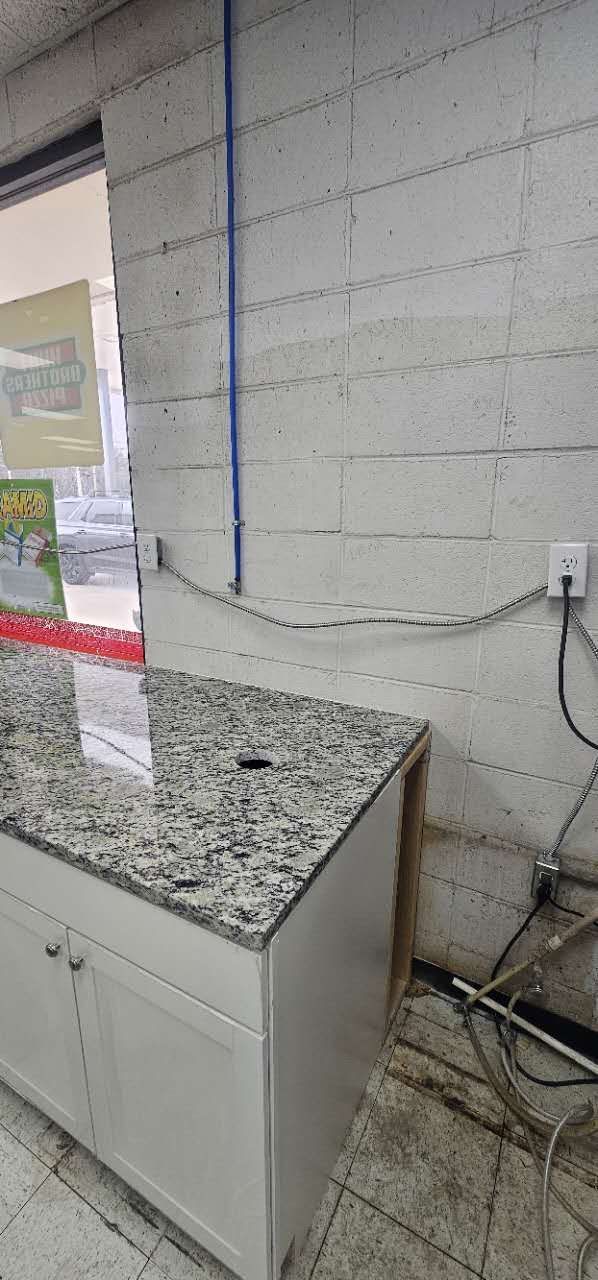 A kitchen with a granite counter top and white cabinets.