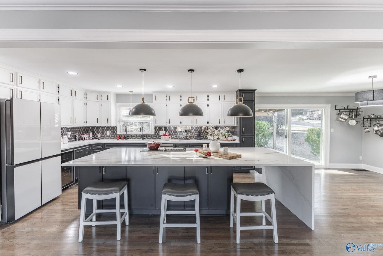 A kitchen with a large island and stools.