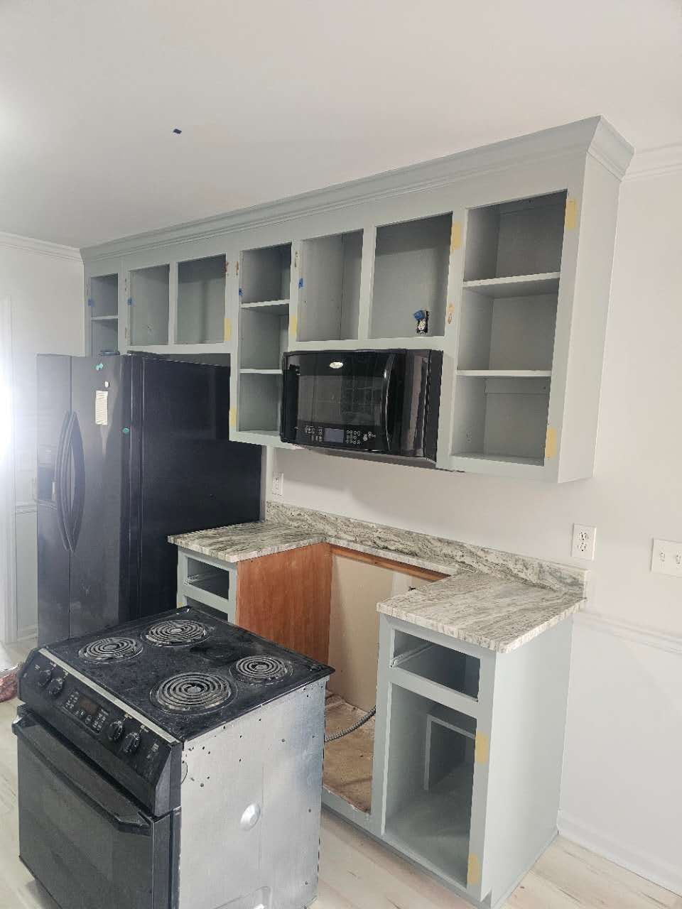 A kitchen with a stove, refrigerator, microwave, and cabinets.