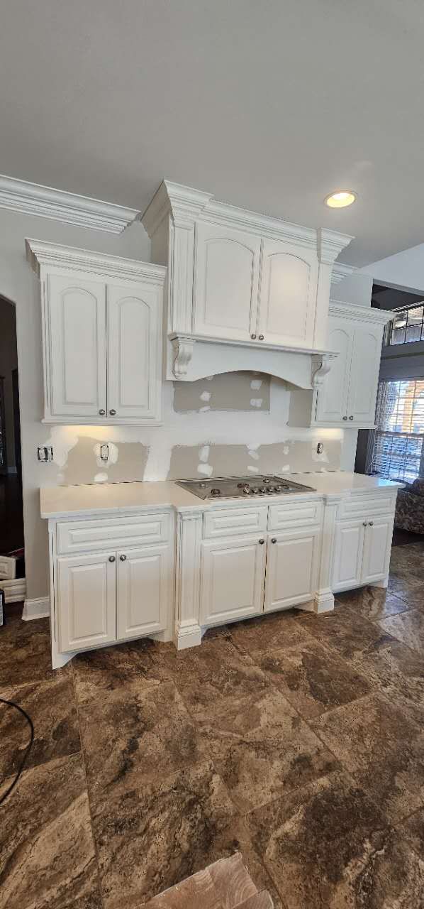 A kitchen with white cabinets and a stove top oven.