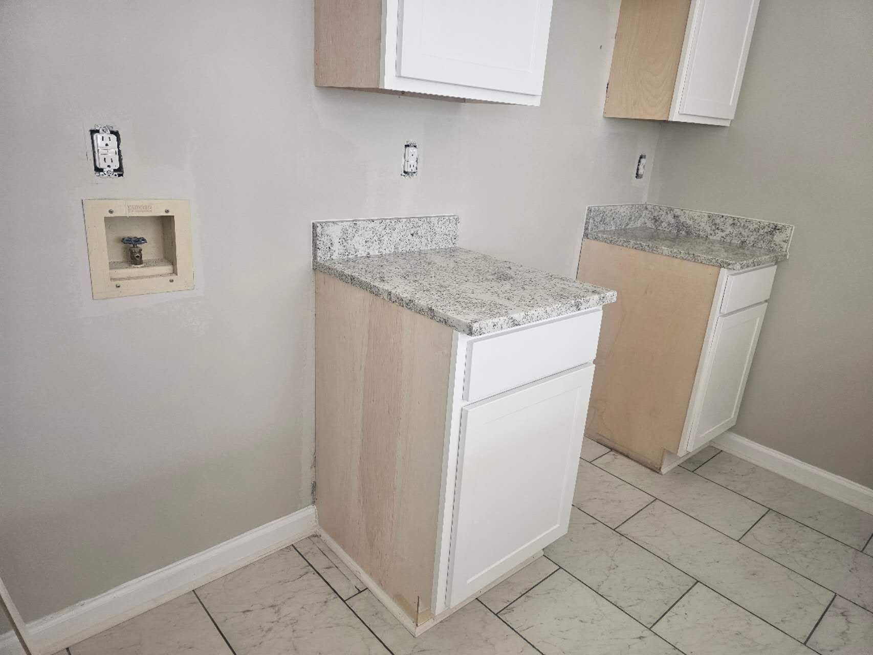 A laundry room with a sink, cabinets, and granite counter tops.