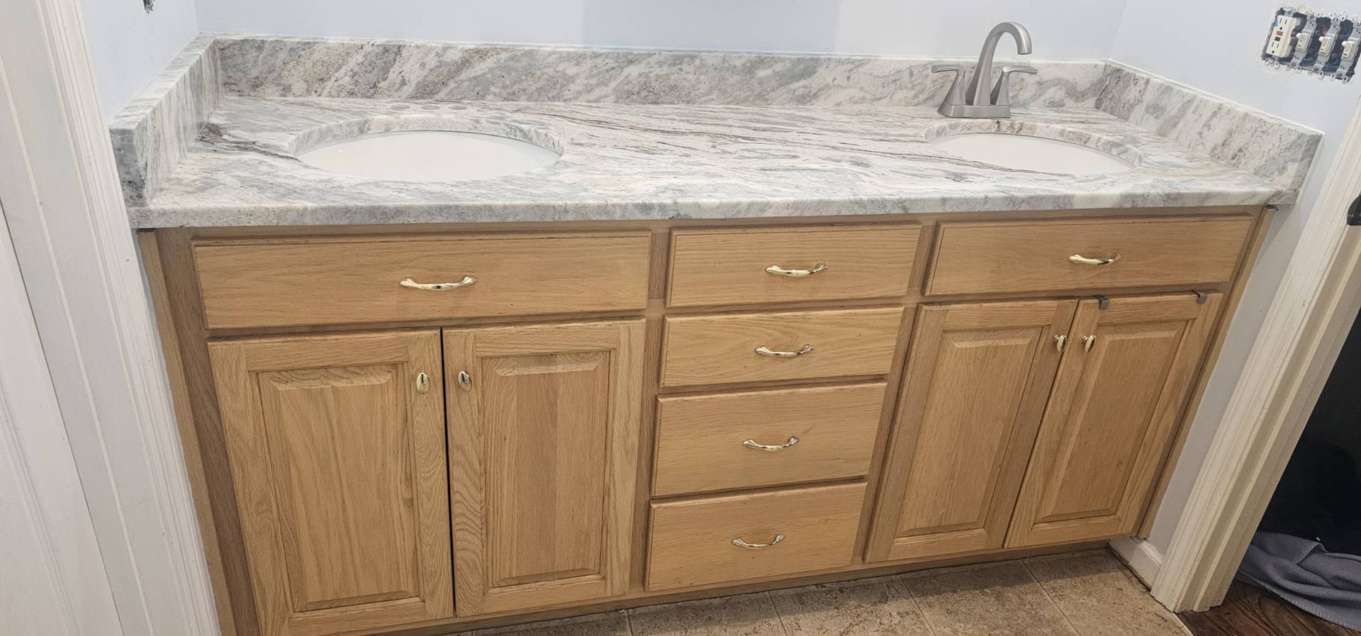 A bathroom vanity with two sinks and a granite counter top.
