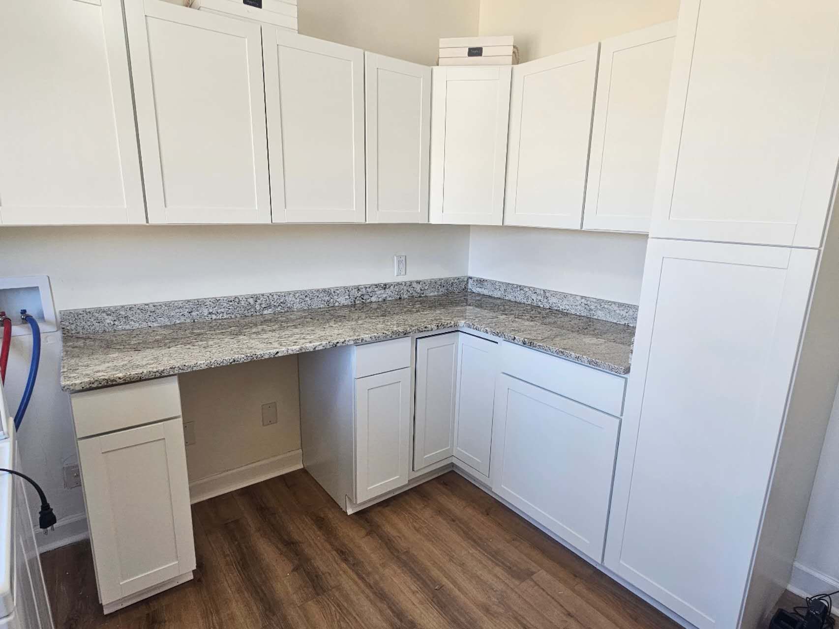 A kitchen with white cabinets and granite counter tops.