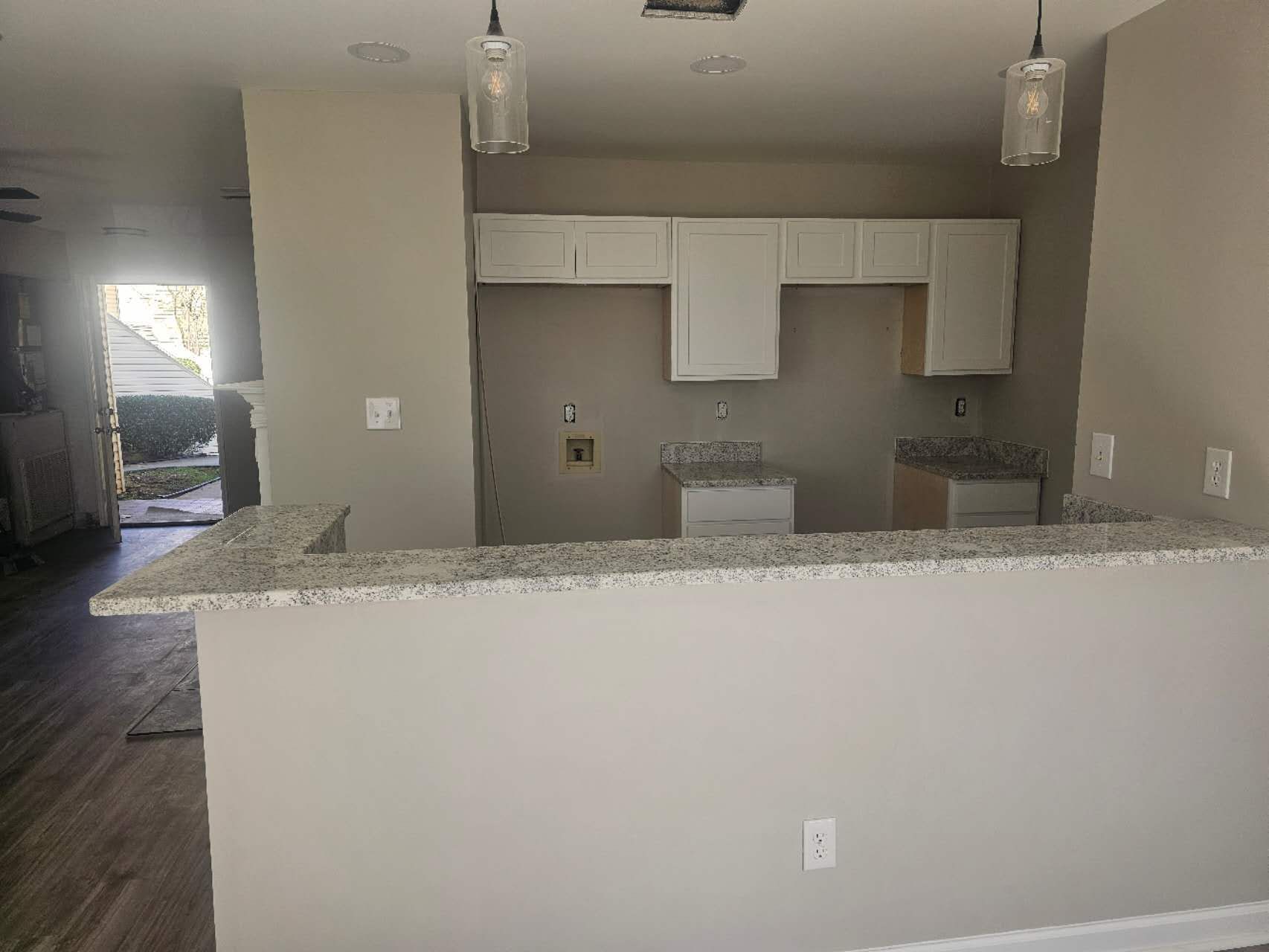 An empty kitchen with a granite counter top and white cabinets.