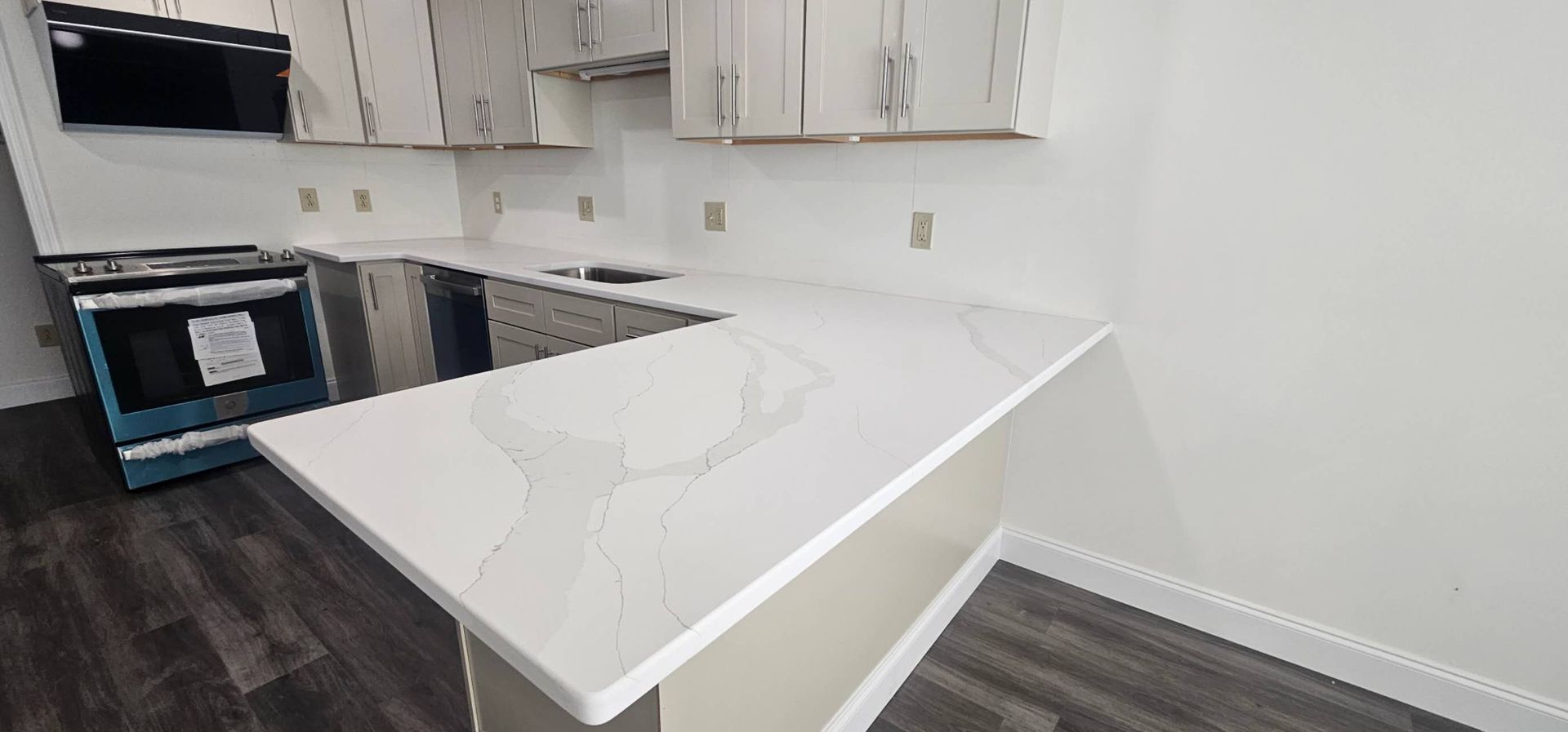 A kitchen with white cabinets, stainless steel appliances, and a white counter top.