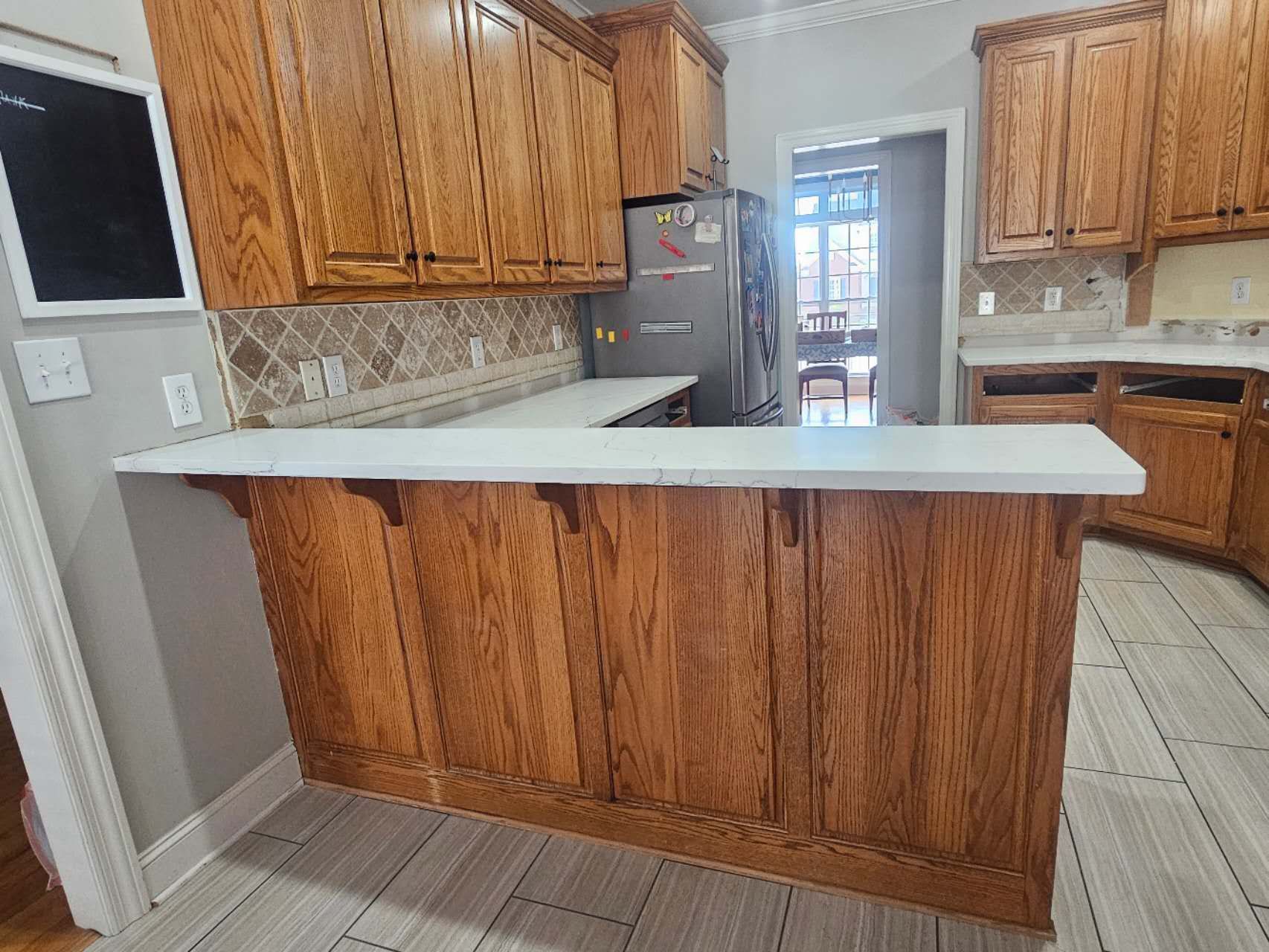 A kitchen with wooden cabinets and a white counter top.