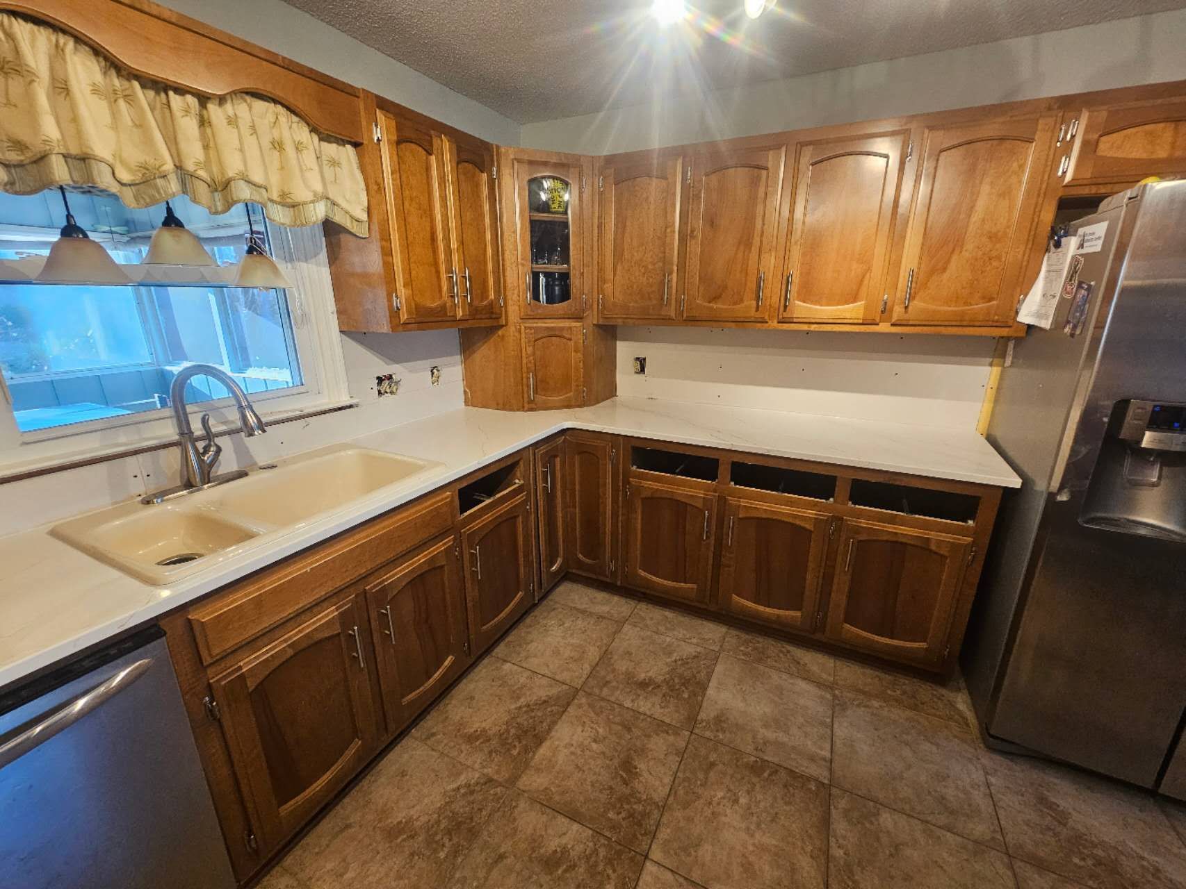 A kitchen with wooden cabinets, stainless steel appliances, a sink, and a refrigerator.