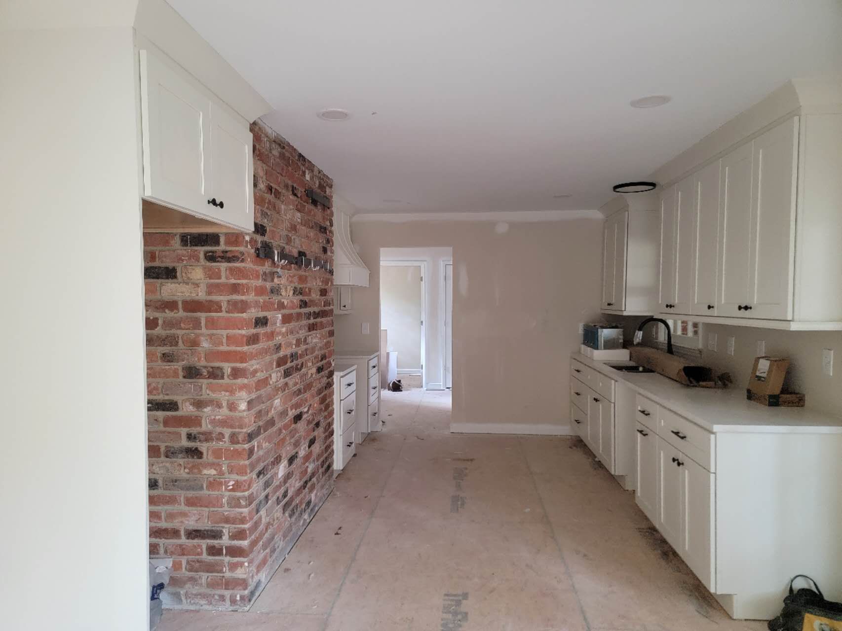A kitchen with white cabinets and a brick wall.