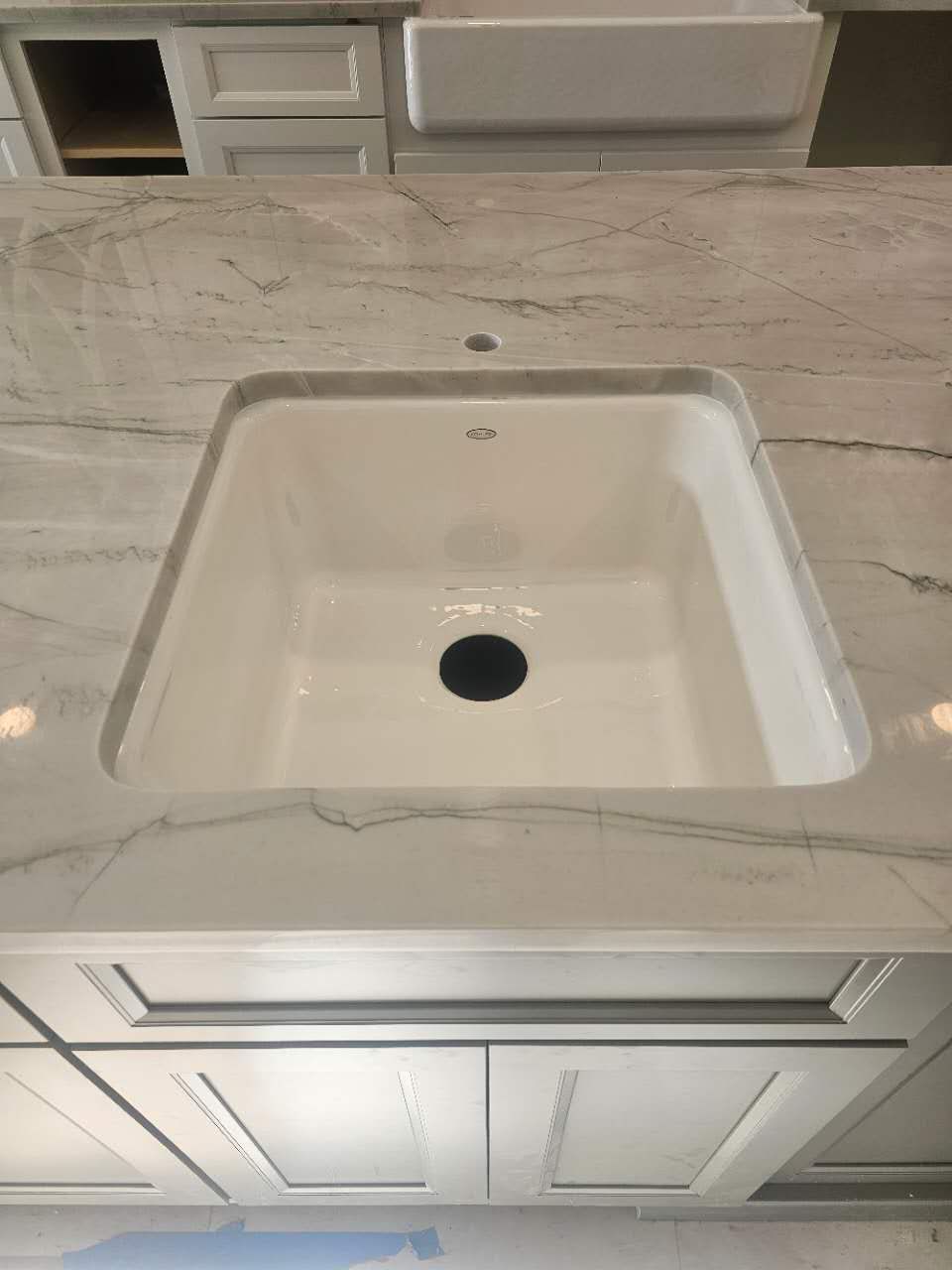 A kitchen sink is sitting on top of a marble counter top.