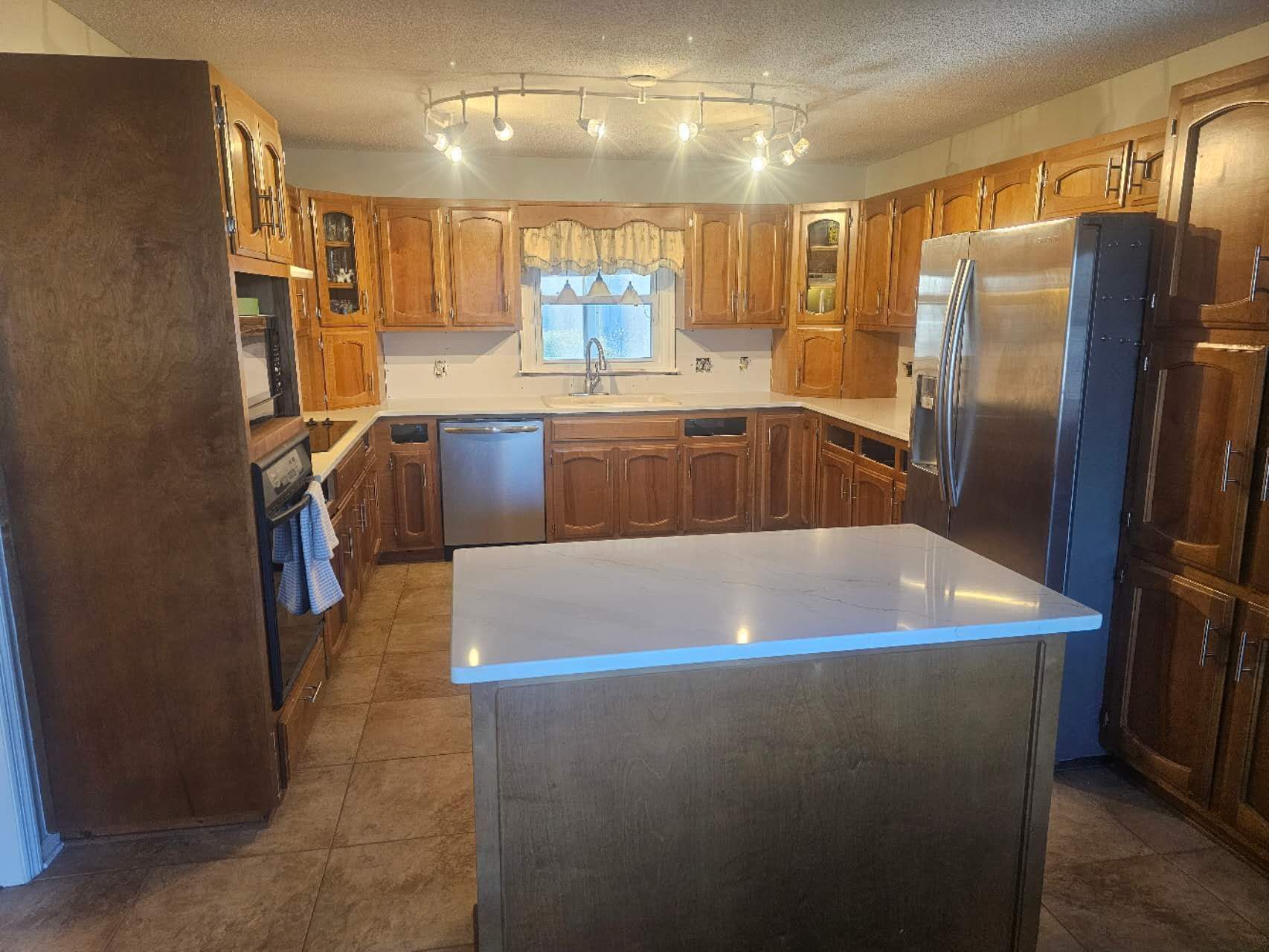 A kitchen with wooden cabinets, stainless steel appliances, and a large island.