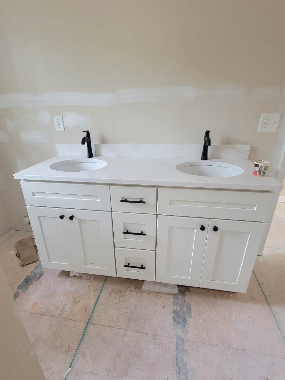 A bathroom vanity with two sinks and black faucets.