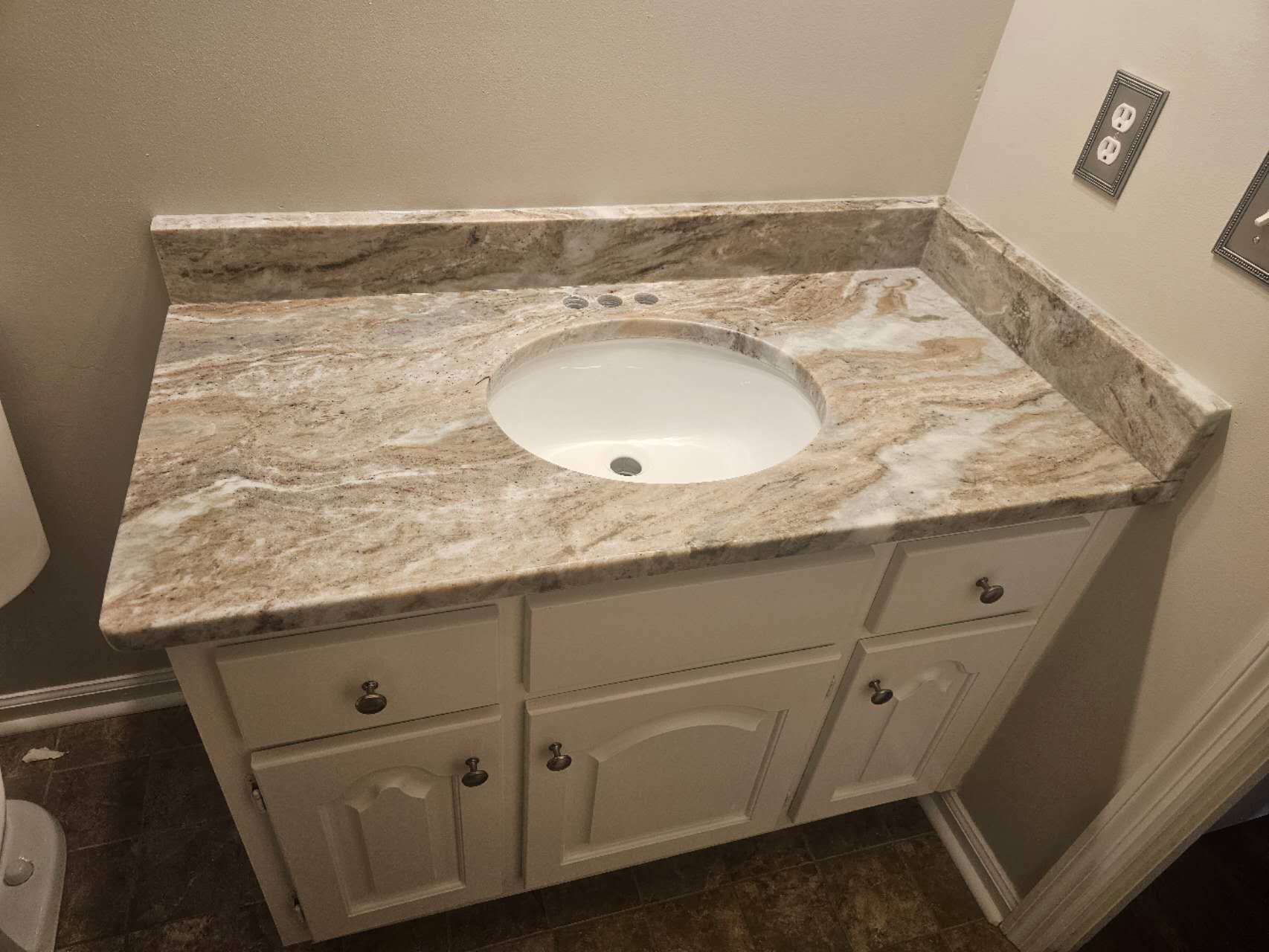 A bathroom vanity with a sink and a granite counter top.