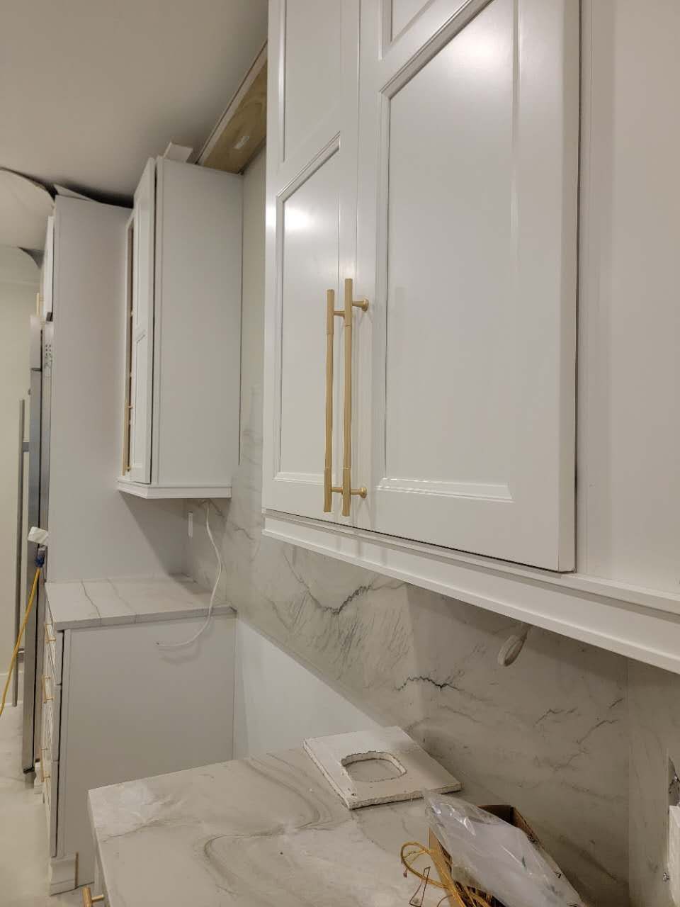 A kitchen with white cabinets and marble counter tops.