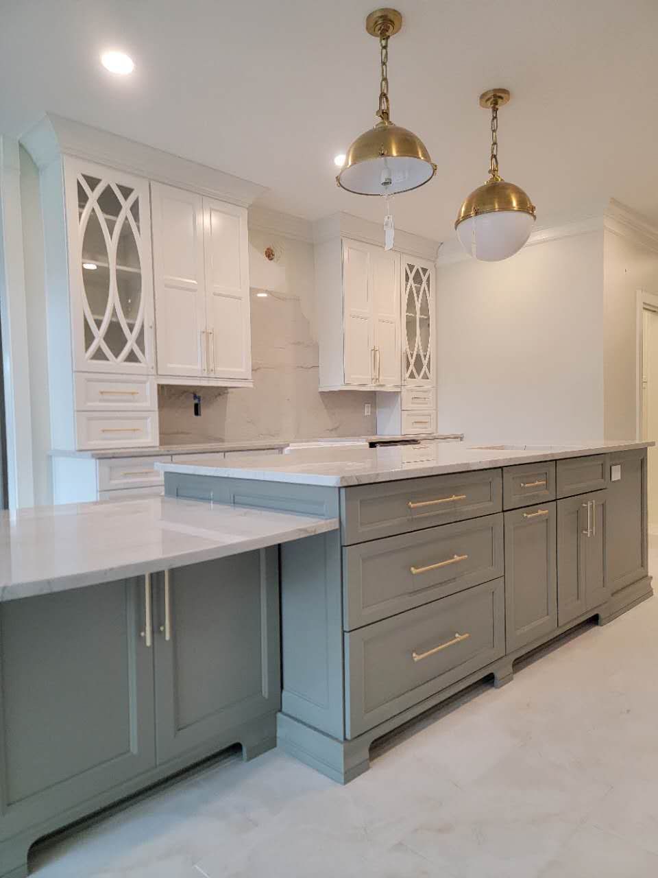 A kitchen with gray cabinets and white counter tops.