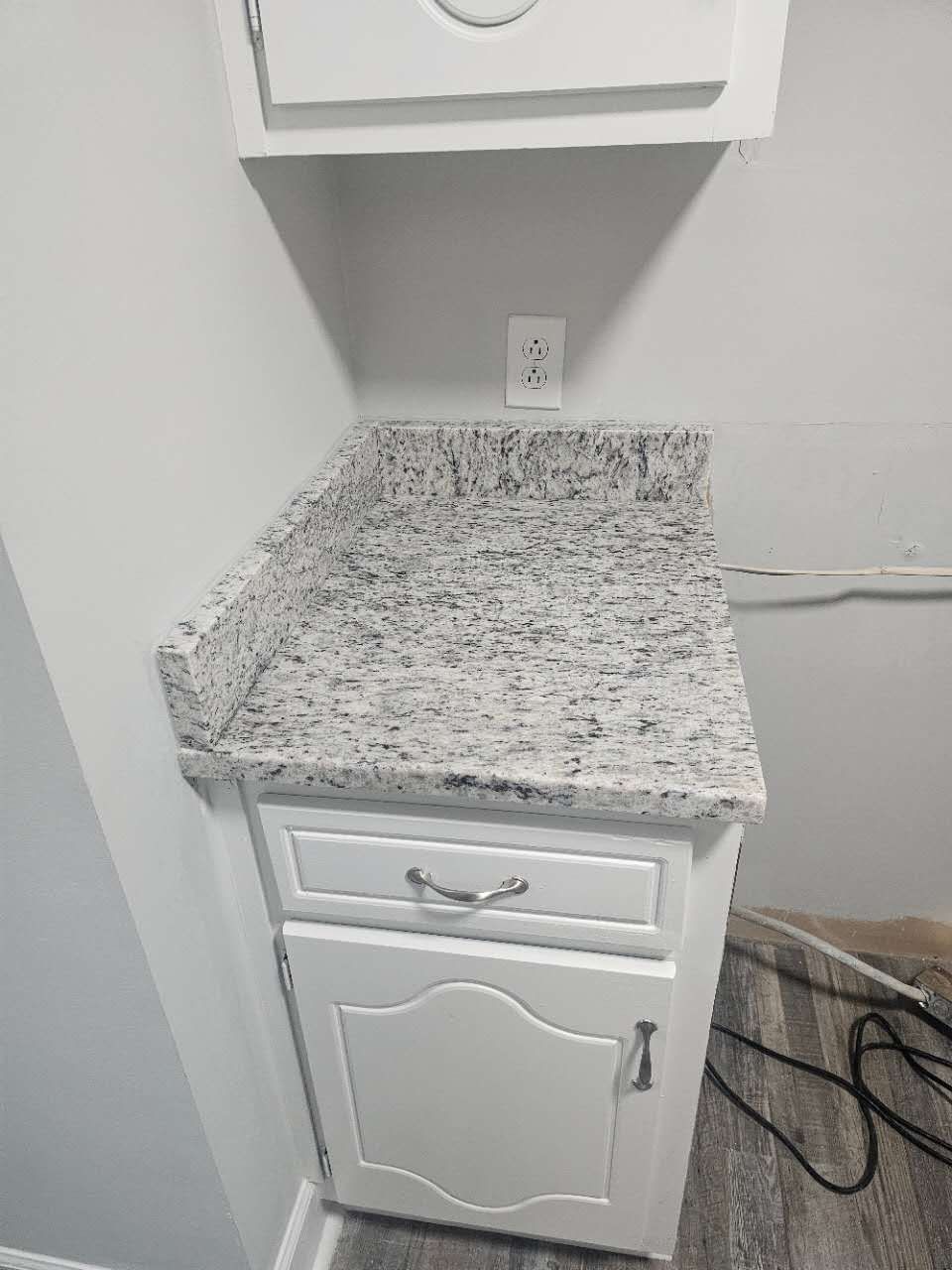 A white cabinet with a granite counter top in a kitchen.