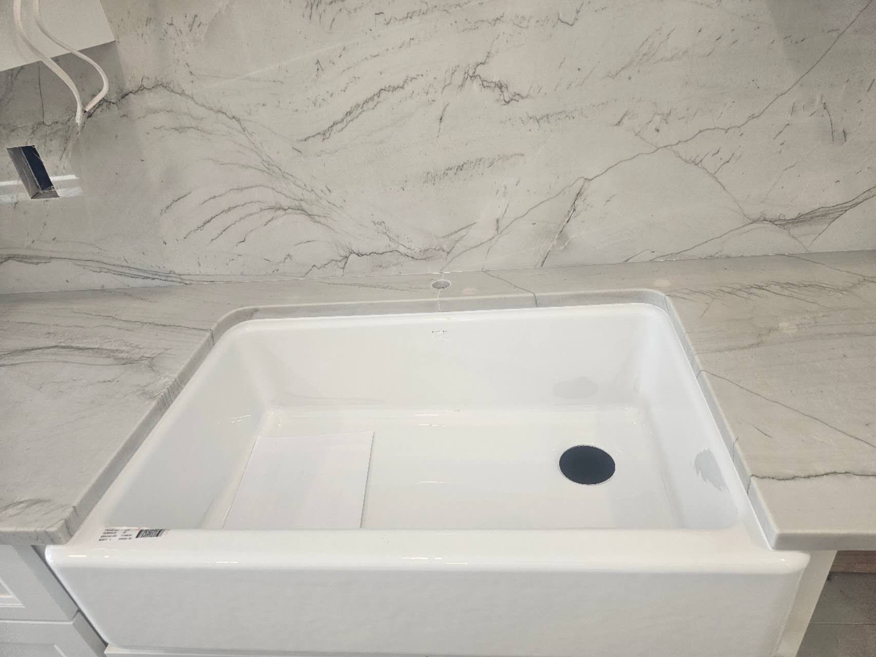 A white sink is sitting on top of a white counter.