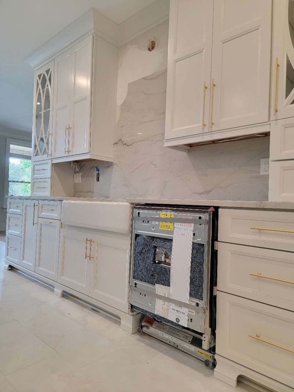 A kitchen with white cabinets, a sink, and a dishwasher.