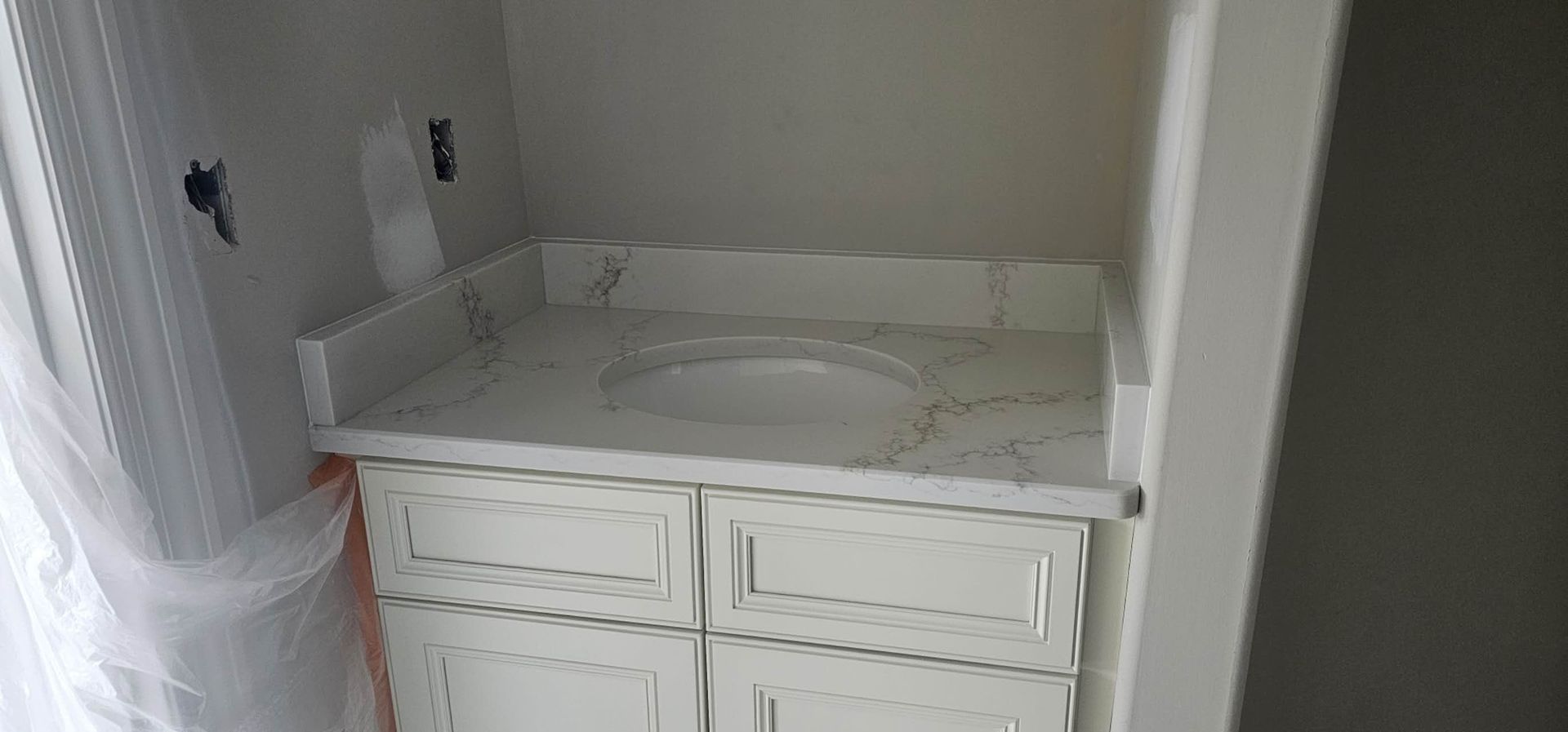 A bathroom vanity with a marble counter top and a sink.