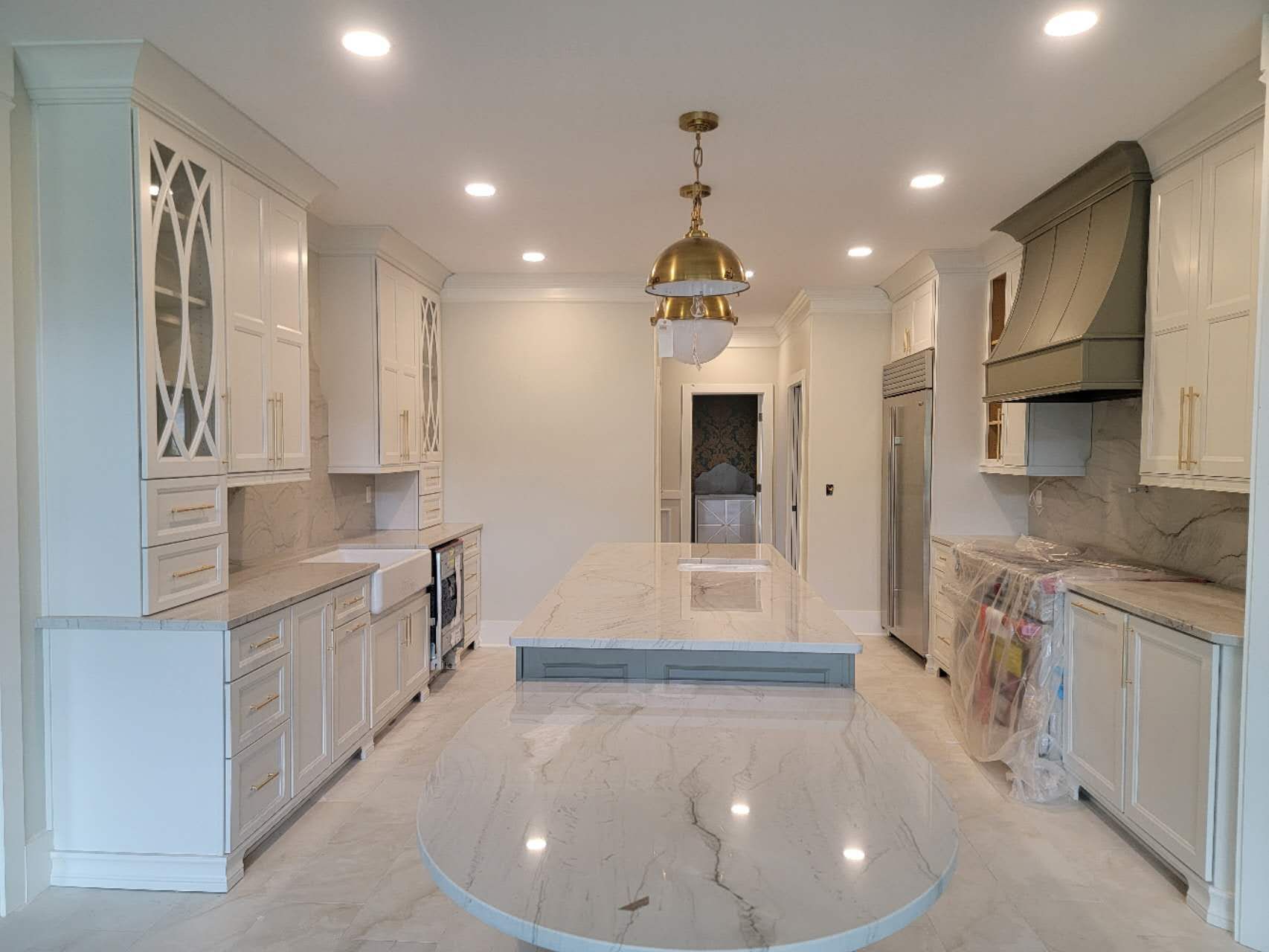 A kitchen with white cabinets and a large island in the middle.