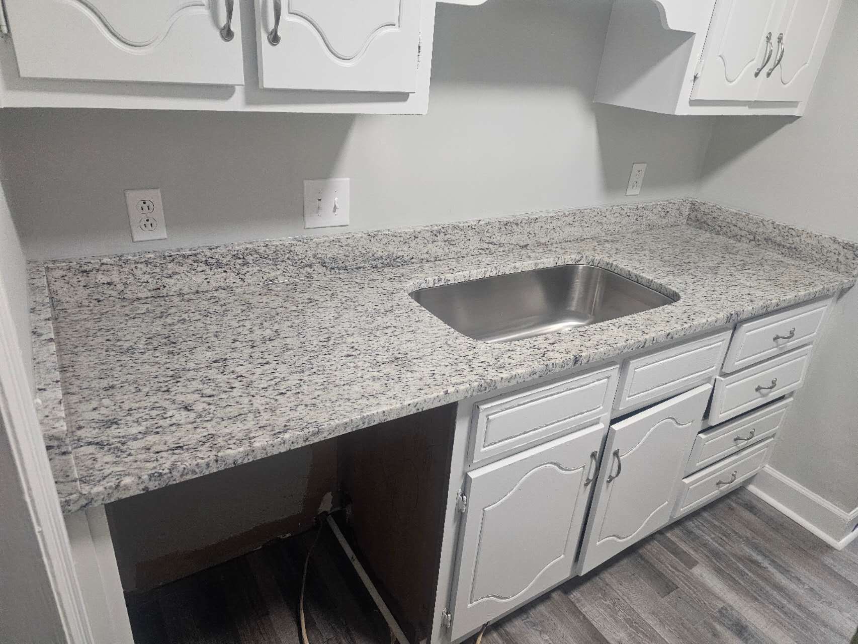A kitchen with granite counter tops and a stainless steel sink.