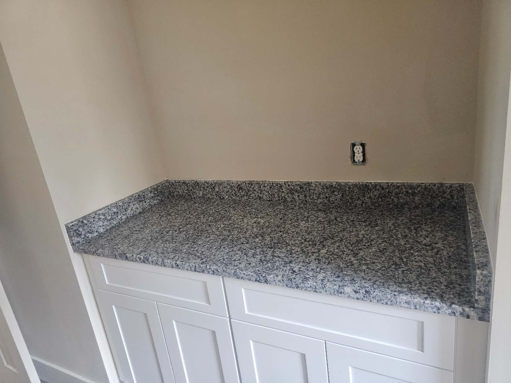 A kitchen with granite counter tops and white cabinets.