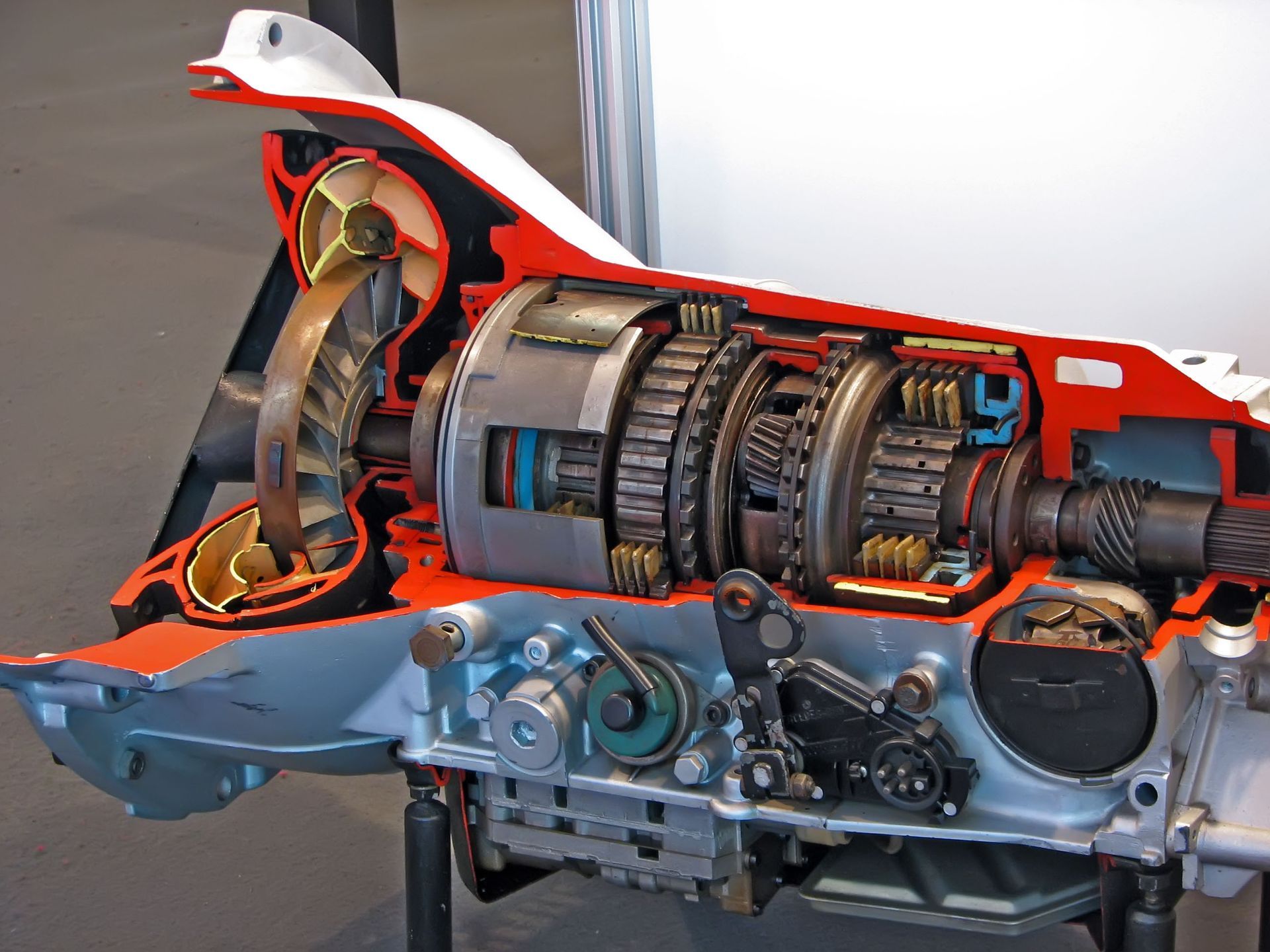 Cutaway view of an automatic transmission, showcasing gears, a torque converter, and hydraulic components; red, silver, and blue colors.