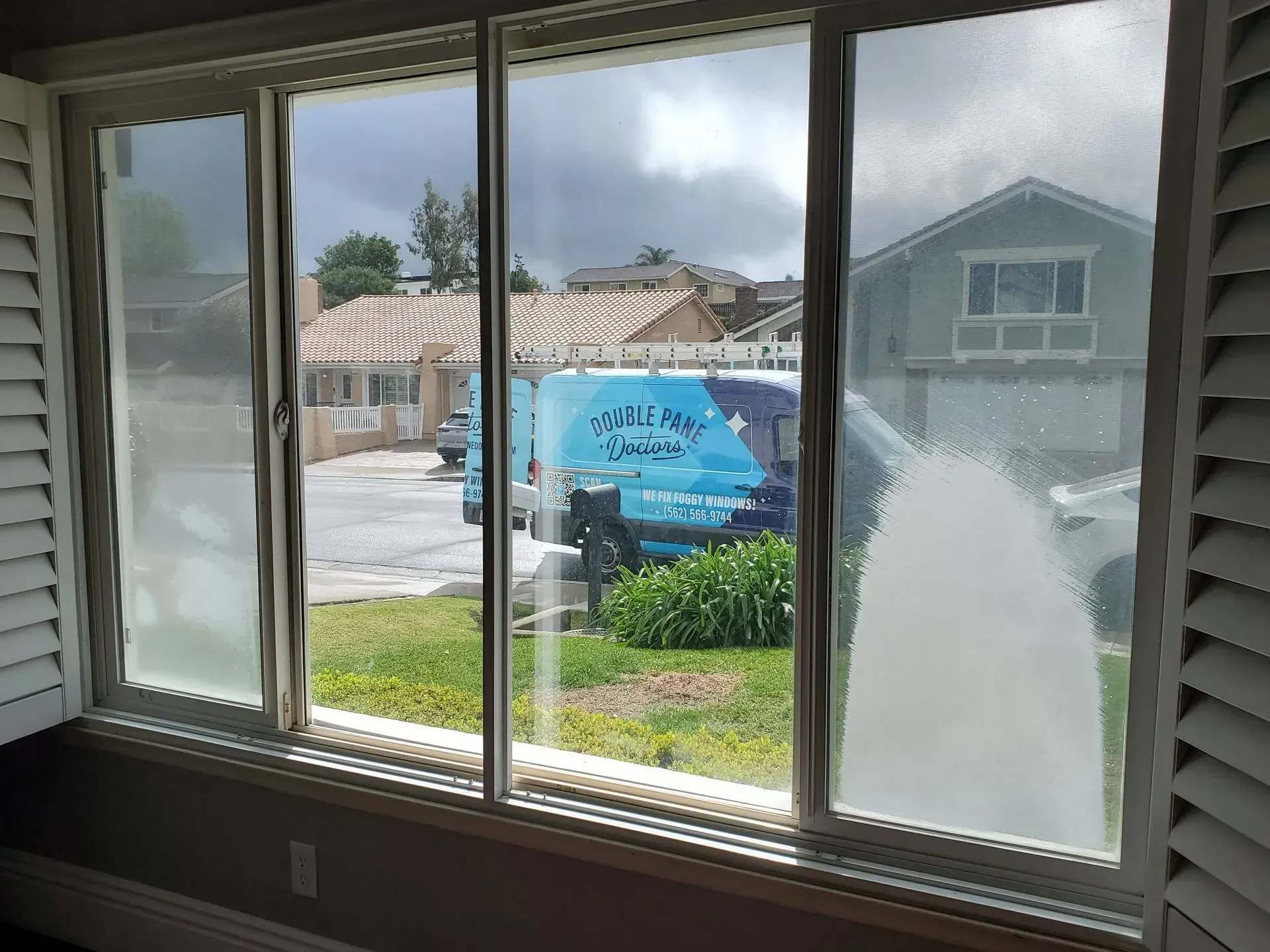 Frosted window, partially open, revealing a cloudy outdoor scene and a utility van.