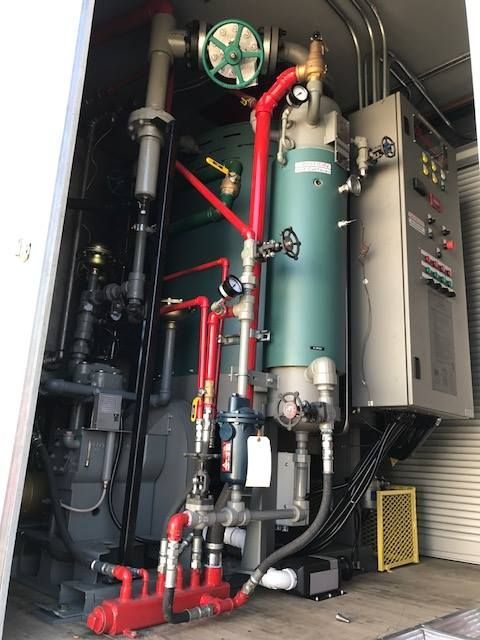 An industrial boiler system with red and grey pipes inside a utility room.