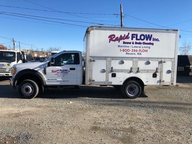 White Rapid Flow Inc. truck with service body, parked outdoors.