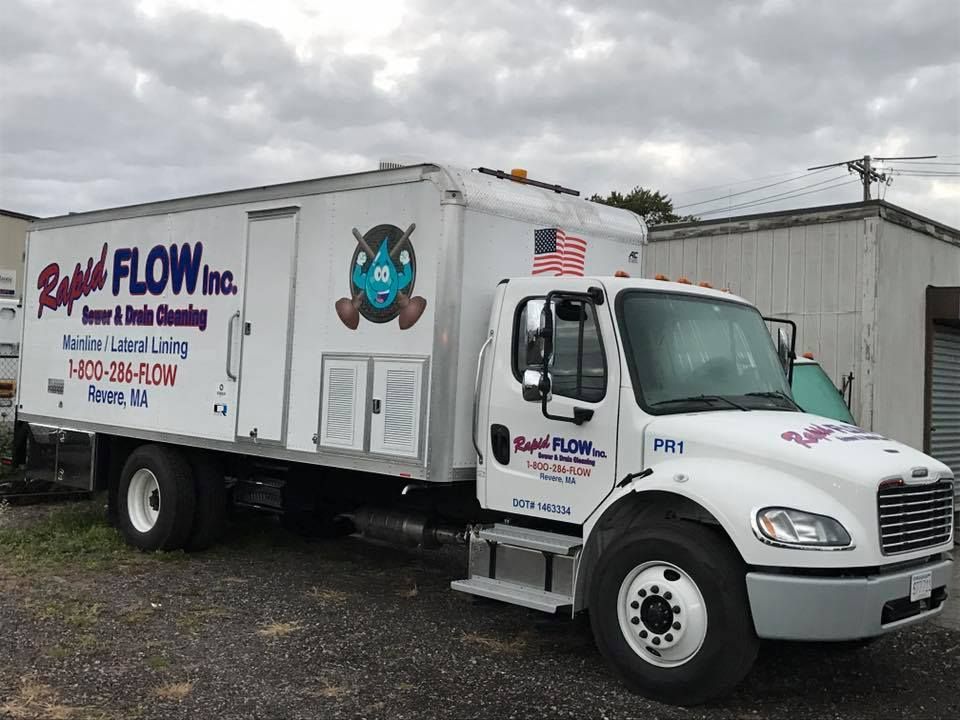 White Rapid Flow Inc. truck, sewer and drain cleaning service, parked in an outdoor setting under a cloudy sky.