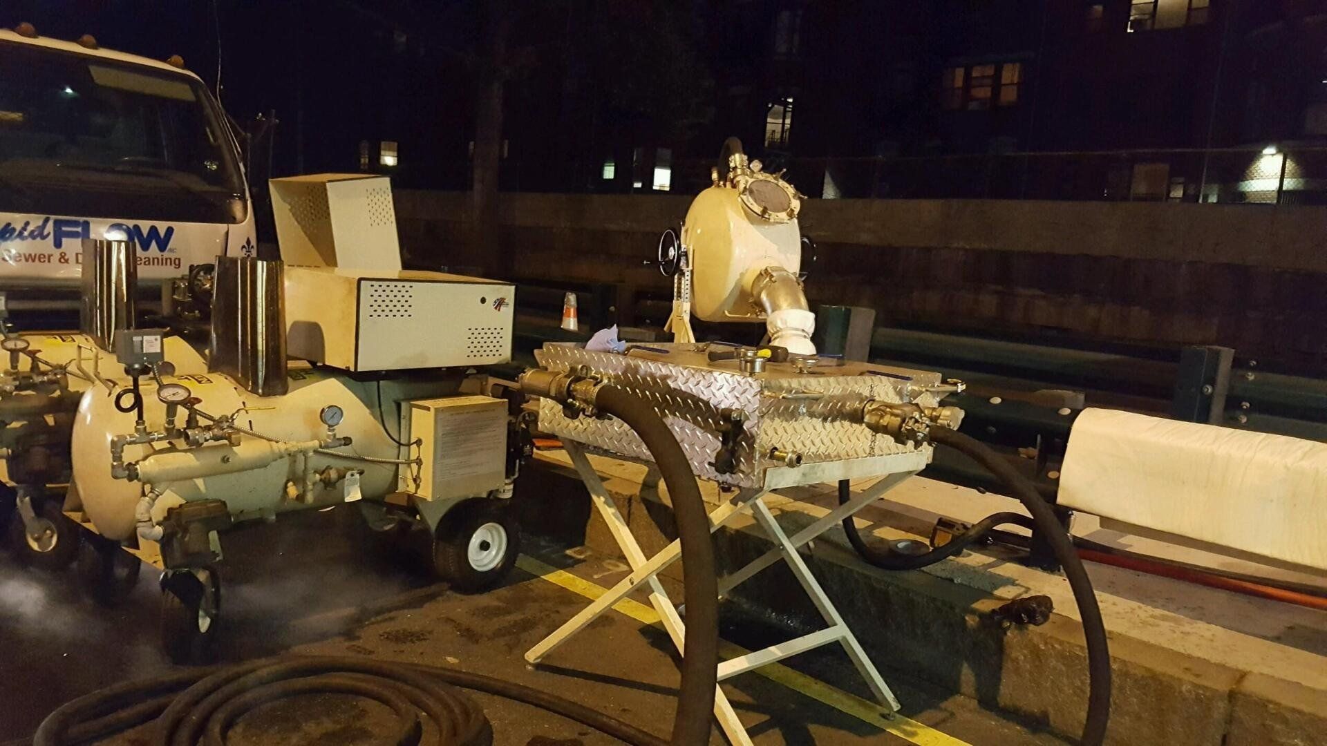 A truck with workers repairing a road at night, emitting steam.
