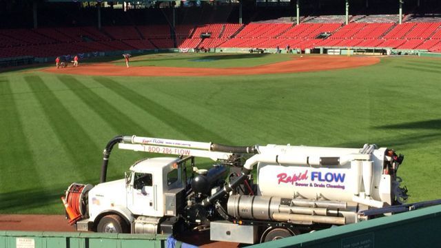 White Rapid Flow truck on a baseball field, red stadium seats in the background.