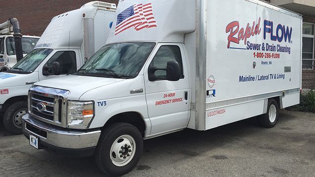 White Rapid Flow sewer and drain cleaning truck with an American flag on the roof.