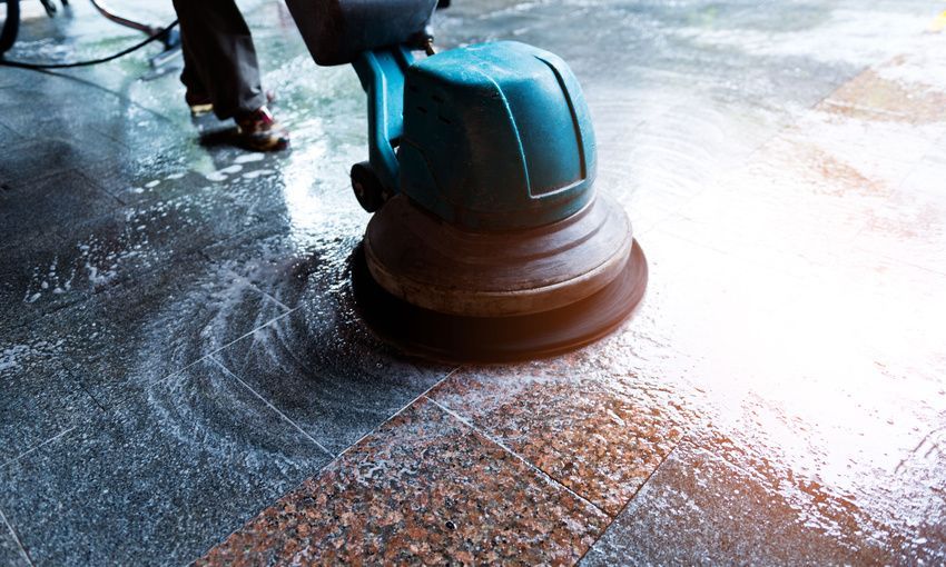 a person is cleaning a tiled floor with a machine