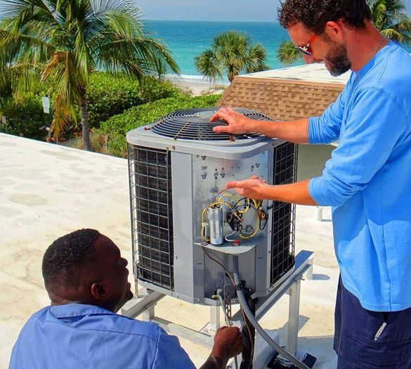 Two men are working on an air conditioner on a roof.