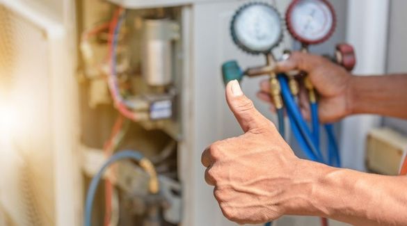 A man is giving a thumbs up while working on an air conditioner.