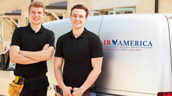 Two men are standing in front of a van that says Air America on it.