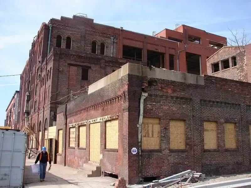 Boarded-up brick building with a person walking past.