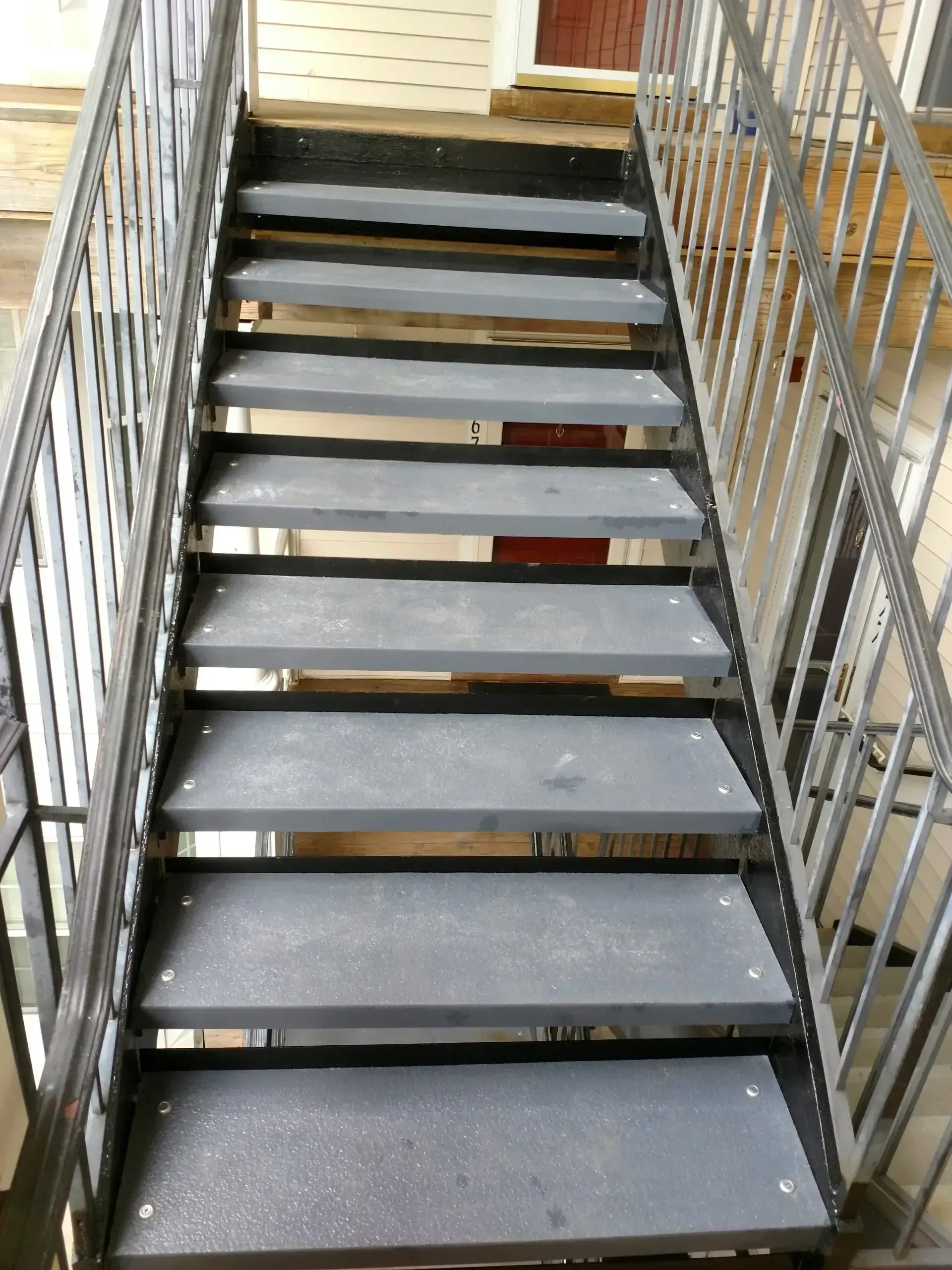 Metal staircase with gray steps and railings, leading upwards.