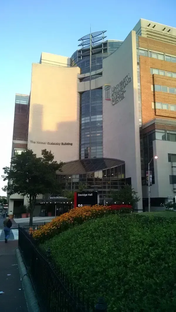 Hospital building with a light-colored facade, windows, and a sign that reads 