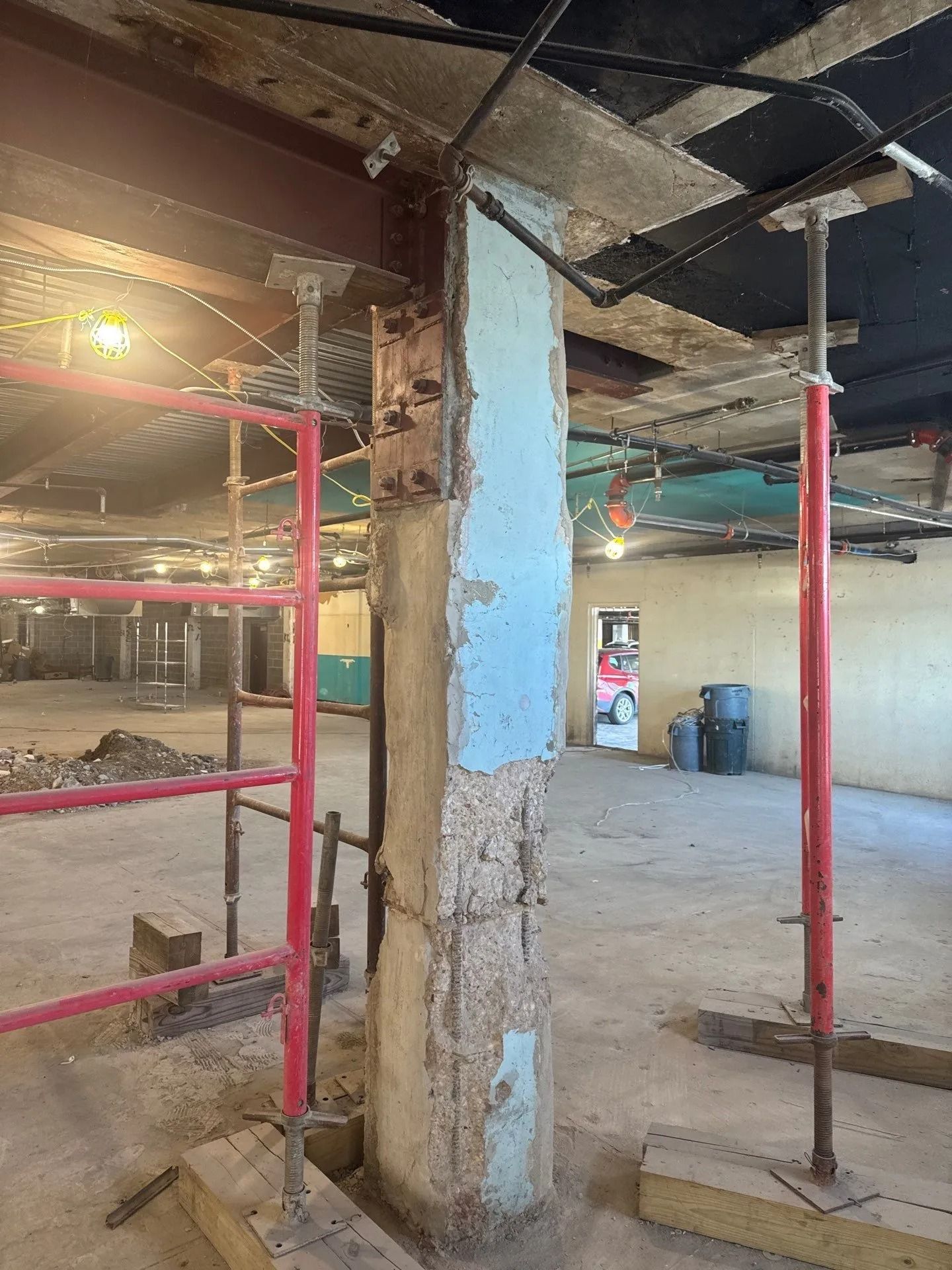 Renovated building interior: a support column is under construction. Red scaffolding and support beams.
