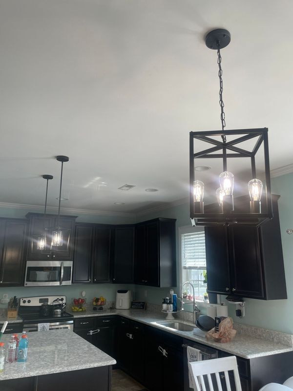 Kitchen with dark cabinets, light countertops, and two black pendant lights.